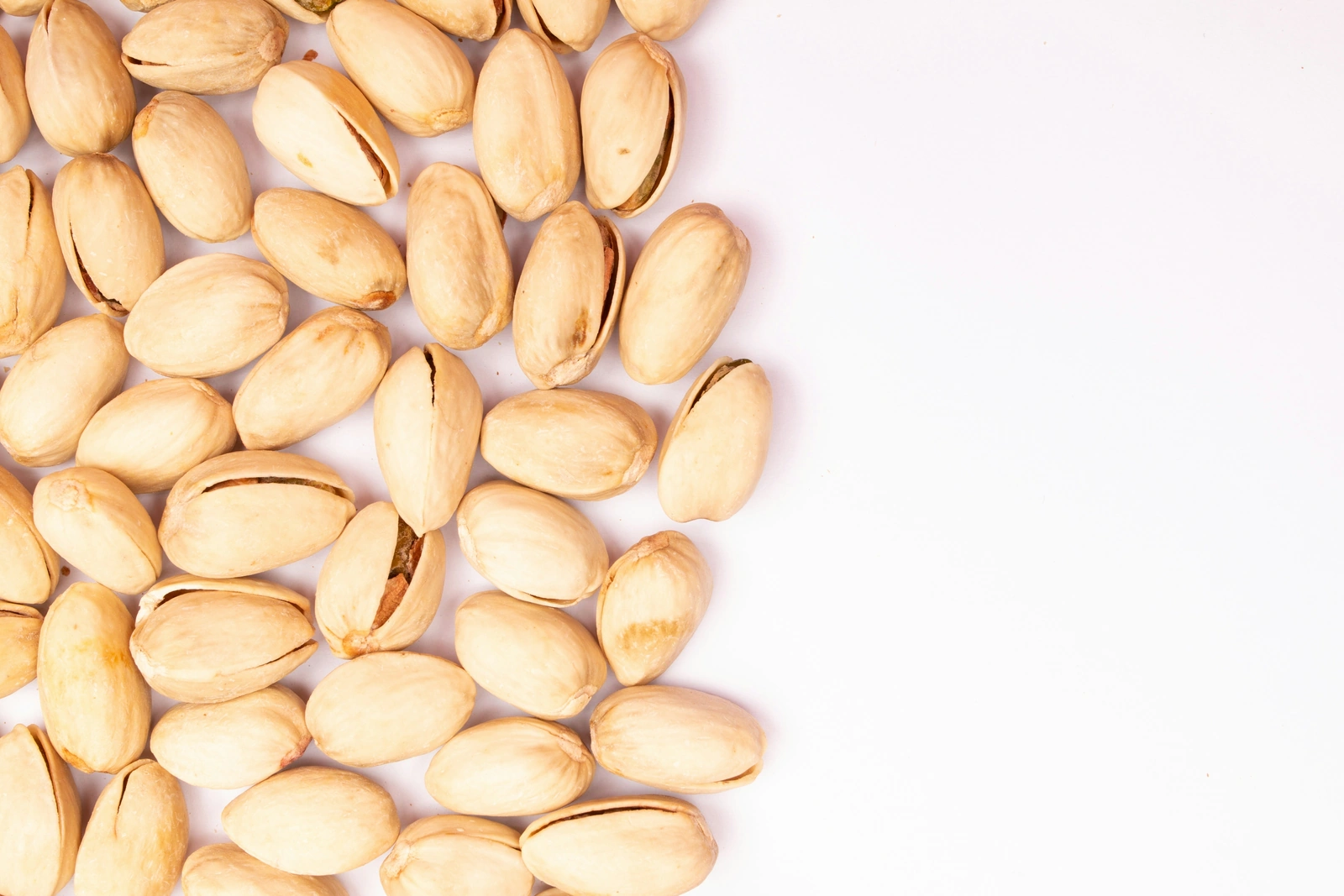 Pistachos con su cáscara abierta sobre un fondo claro